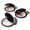Open compacts of dual-tone powder makeup are displayed on a light background