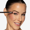 Model holding a  short, broad shape brush near her eyes, showcasing a pigment packing brush