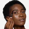 Model holding and showcasing a black brow liner