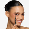 Model holding a gel eye liner pencil near her eyes, showcasing a brown eyeliner look