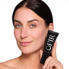 A smiling person holding a black tube labeled "OFIR" containing one fluid ounce (30 mL) against a white background.