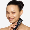 Model holding a primer bottle of OFIR 's Skin Prep, showcasing smooth, radiant, dewy even skin.