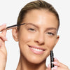 model applying OFIR Brow Tonic in shade Sumac with a fine brush, shaping natural, full-looking brows