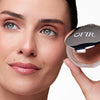 Person showcasing OFIR compact with a soft, natural makeup look, highlighting eyes and lips complemented by the product.