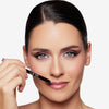 Model holding a lip liner to her mouth, showcasing a pink shade