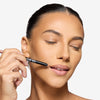 Model holding a lip liner to her mouth, showcasing a light nude shade