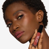 Model holding and showcasing a soft brown lipstick