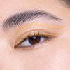Close-up of a person's eye adorned with dual-layered gold eyeliner, featuring a bold, shimmering line above the crease and a matching line along the lash line.