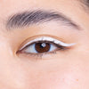 Close-up of a brown eye with bold white eyeliner creating a modern, winged effect, complemented by well-groomed eyebrows.