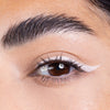Close-up of a neatly groomed eyebrow and eye featuring dramatic white eyeliner applied with a sleek winged design.