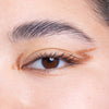 Close-up of an eye with winged eyeliner featuring a copper hue, showcasing bold brows and clean application.
