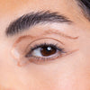 Close-up of a brown eye with artful metallic eyeliner, featuring a winged design and highlighting on the brow bone.