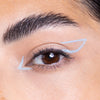 Close-up of an eye with neatly groomed eyebrows and a creative white eyeliner design extending from the corners.