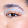 Close-up of a brown eye with light blue eyeliner applied in a sleek, curved line above the eyelid.