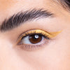 Close-up of an eye featuring bold, shimmering gold eyeliner applied in a sleek, cat-eye style.