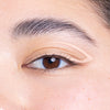 Close-up of a person's eye featuring neatly groomed eyebrows and a delicate application of cream eyeliner emphasizing the eyelid.