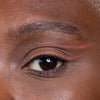 Close-up of a person's eye with pink graphic eyeliner design, showcasing precise makeup application.
