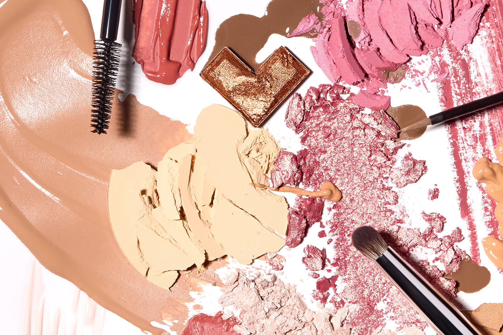 A colorful array of makeup products, including foundation, eyeshadow, blush, and mascara, arranged artistically with application brushes on a white background.