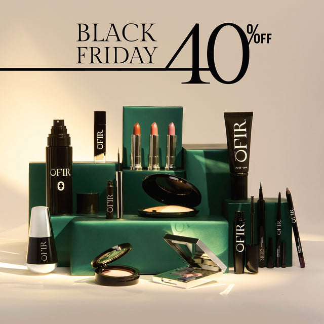 A collection of OFIR beauty products, including lipsticks, eyeliners, and foundation, displayed on green stands with a 