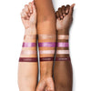 Three forearms displaying swatches of four different eyeshadow shades labeled Mystic Topaz, Violet Prism, Pink Quartz, and Plumstone.