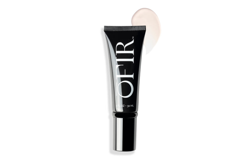 Black tube labeled "OFIR" with a smear of light-colored cream beside it, suggesting a cosmetic product.