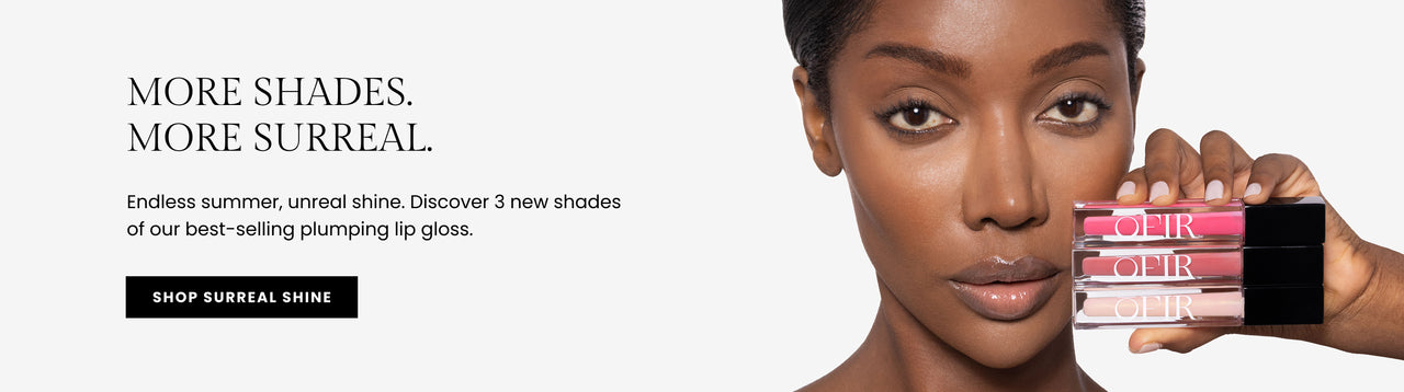 Promotional banner for new product. Text reads "More Shades. More Surreal" followed by "Endless summer, unreal shine. Discover 3 new shades of our best-selling plumping lip gloss," and a "Shop Surreal Shine" button