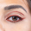 Close-up of a well-defined eyebrow and eye adorned with a warm-toned eye shadow, featuring sleek eyeliner for a polished look.