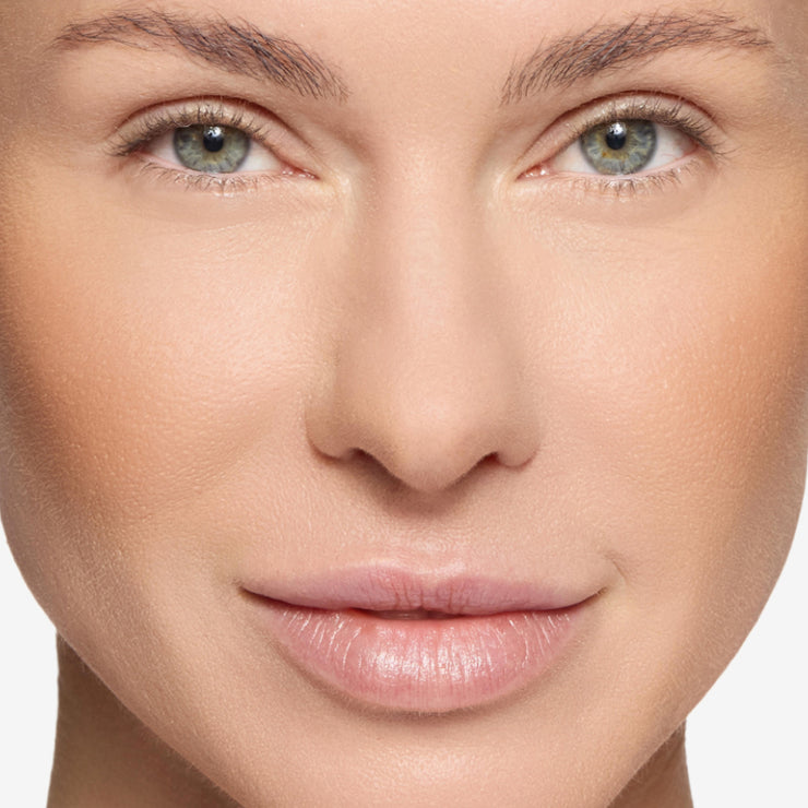 Front-facing close-up of a model with natural makeup, even complexion, softly defined brows, and minimal glow, emphasizing smooth skin and balanced features