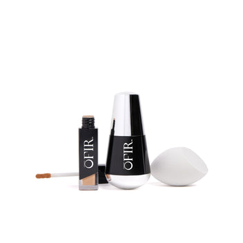 A sleek set of cosmetics, including a bottle of foundation with a silver cap, a concealer with an applicator, and a white makeup sponge.