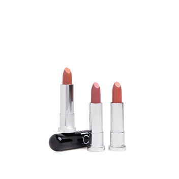 Three lipsticks in varying shades of pink and nude, with two standing upright and one placed on its side with a shiny black cap.